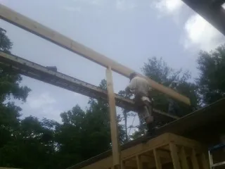 Carpenter setting a ridge beam over a new addition frame — Ice Dam Removal by Roofing Brothers in Allons