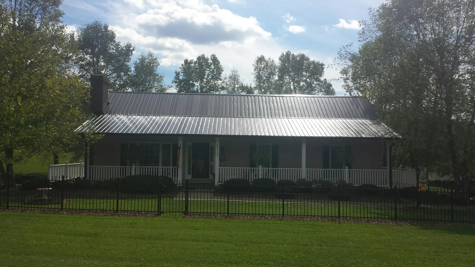 Gray metal roof on a brick ranch with a full width front porch — Gutter Guard Installation work by our crew in Allons