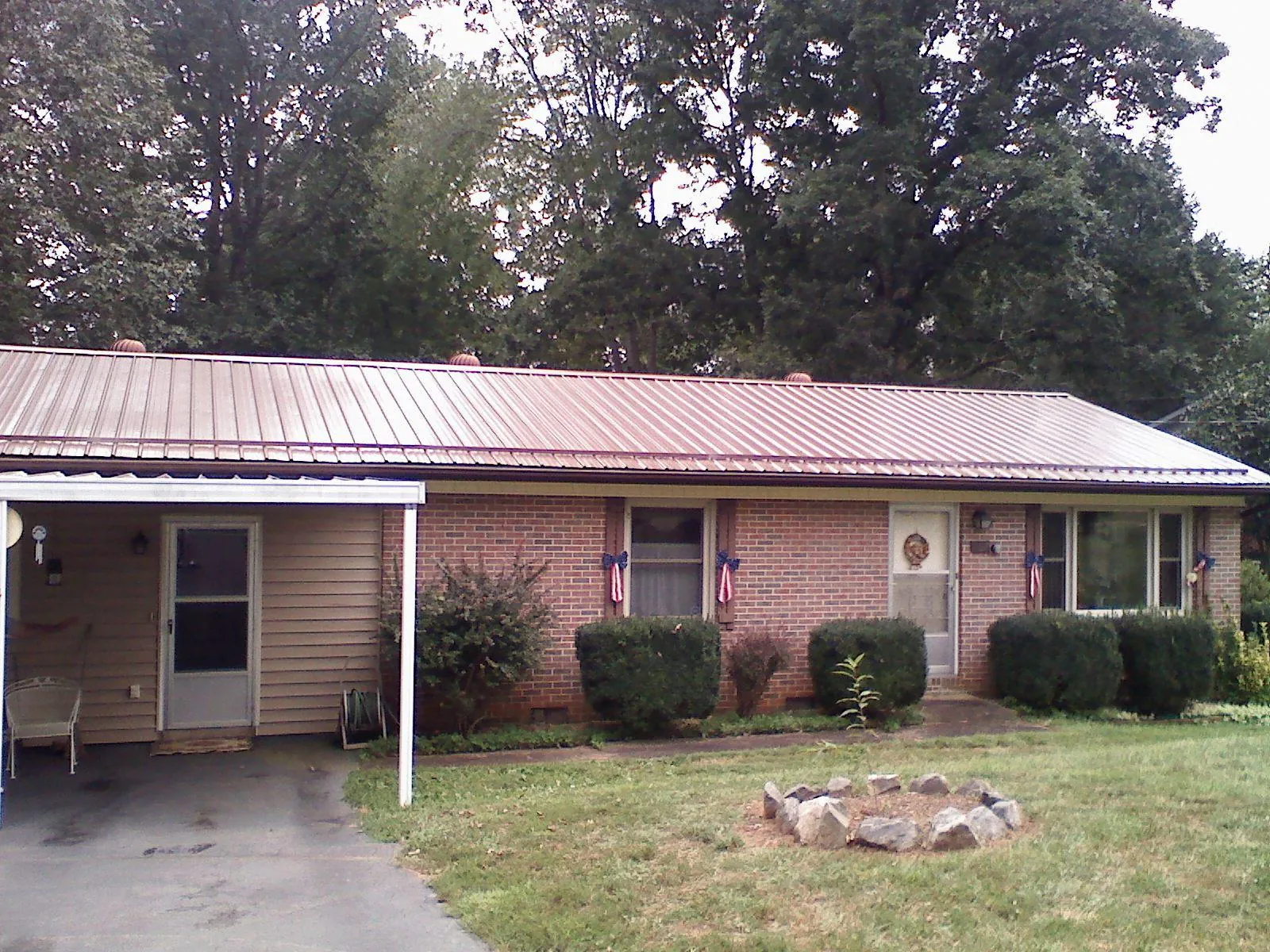 Bronze metal roof and carport on a brick ranch home — Roof Repair work by our crew in Allons